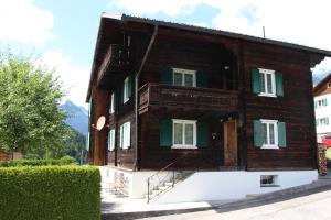 uma casa de madeira com persianas verdes e um alpendre em Haus Danna em Sankt Gallenkirch