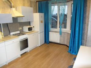 ウファにあるApartment Chernyshevskogo 71/1のキッチン(白い家電製品付)、青いカーテン付きの窓
