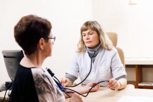a woman sitting at a table with a stethoscope around her neck at Meresuu Spa & Hotel in Narva-Jõesuu