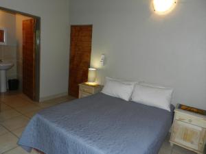 a bedroom with a bed with a blue blanket and white pillows at Impalas Walk in Marloth Park