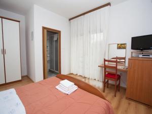 バスカにあるDalibor Baska Roomsのベッドと机とテレビのある寝室