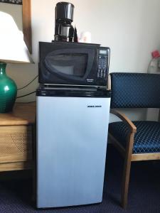 a microwave on top of a refrigerator next to a chair at Best Inn in Petersburg