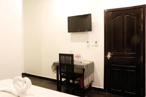 Habitación con mesa y TV en la pared. en Pool Party Hostel en Siem Riep