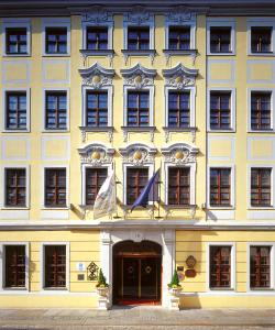 un grande edificio giallo con bandiere di fronte di Romantik Hotel Bülow Residenz a Dresda