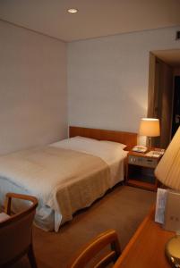 1 dormitorio con 1 cama y escritorio con lámpara en Kojima Puchi Hotel, en Kurashiki