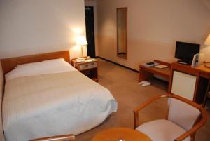 倉敷市にある児島プチホテルのベッド、デスク、椅子が備わるホテルルームです。
