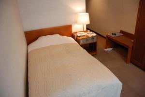 1 dormitorio con 1 cama y 1 mesa con lámpara en Kojima Puchi Hotel, en Kurashiki