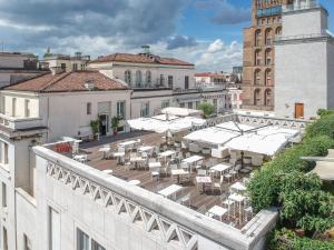 einen Balkon mit Tischen und weißen Sonnenschirmen auf einem Gebäude in der Unterkunft Hotel Vittoria in Brescia