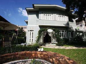 a white cat sitting on a brick wall in front of a house at Lada House in Lampang