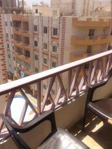 einen Stuhl auf einem Balkon mit Blick auf die Gebäude in der Unterkunft شقة شاطيء النخيل -بالما كورت in Alexandria