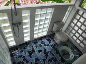 a bathroom with a shower and a toilet and windows at Hotel Pura Vida in Puerto Viejo