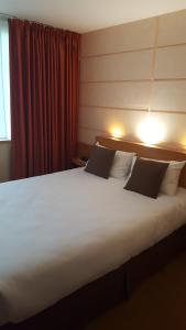 een groot wit bed in een hotelkamer bij Contact Hôtel du Parc in Orvault