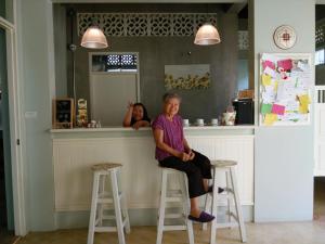 an older woman sitting on a bar in front of a counter at Lada House in Lampang