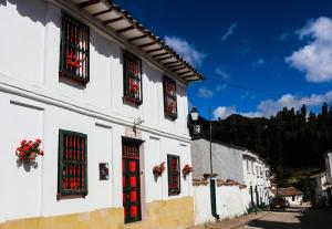 a white building with red windows on a street at Hotel Otti Colonial in Monguí