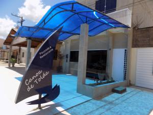 a house with a blue roof with a sign in front of it at Pousada Canoa de Tolda in Piranhas