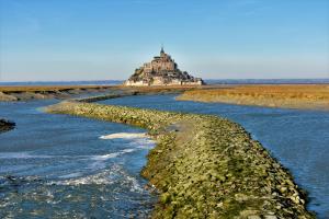 uma ilha na água com um edifício ao fundo em Chambres d'Hôtes l'Hermine em Val Couesnon