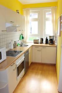 cocina con paredes amarillas y armarios blancos en Ferienwohnung Villa Parkblick, en Oberhof