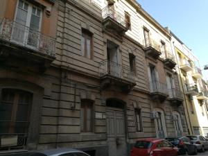 budynek z samochodami zaparkowanymi przed nim w obiekcie Ursino rooms apartment w Katanii