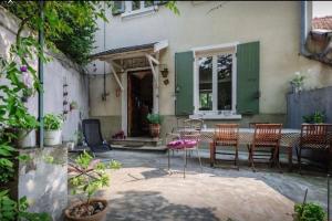 un patio con sillas y una mesa frente a una casa en Maison de charme 1930 proche Lyon en Lentilly
