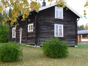 ViggeにあるBrukstugaの白窓と茂み2本の黒い家