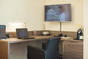 een bureau met een laptop en een televisie aan de muur bij Parkhotel Ahrbergen in Giesen