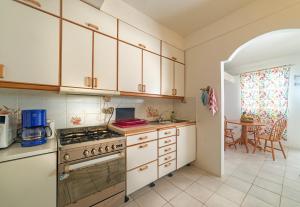 a kitchen with white cabinets and a stove top oven at Royal Palm Holiday Apartment in Méro