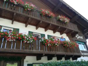 duas pessoas olhando para fora de uma varanda com flores em B&B Bucaneve em Vigo di Fassa