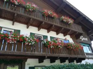two people looking out of a balcony with flowers at B&B Bucaneve in Vigo di Fassa