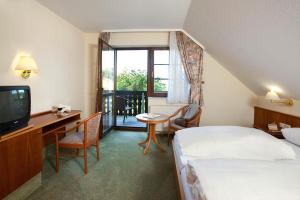 a hotel room with a bed and a desk and a television at Hotel zum Taufstein in Sparhof