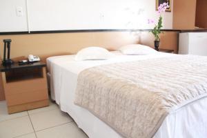 um quarto com uma cama branca e um telefone em Taba Hotel em Jaciara