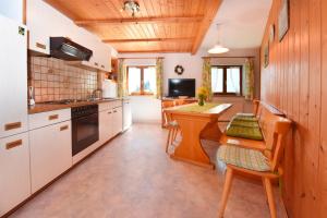 eine Küche mit weißen Schränken sowie einem Tisch und Stühlen in der Unterkunft Lindenhof in Sulzberg