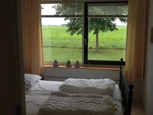 a bedroom with two beds and a window with a view at Stinswoning "de Wadden" in Tzummarum in Tzummarum