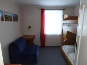 een slaapkamer met een bed en een blauwe stoel en een raam bij Chata Bludička in Deštné v Orlických horách