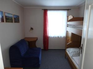 a bedroom with a bed and a blue chair and a window at Chata Bludička in Deštné v Orlických horách