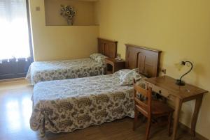 a room with two beds and a table and a desk at Agroturismo Abaienea in Vitoria-Gasteiz