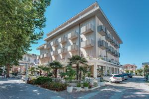 a large white building with palm trees in front of it at Hotel Garden in Bellaria-Igea Marina