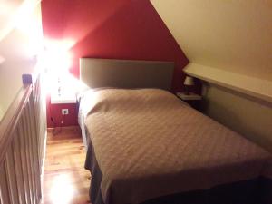 a small bedroom with a bed and a red wall at gite la Pinetterie in Civray-de-Touraine