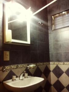 y baño con lavabo y espejo. en Cabañas Aliksir en Cosquín