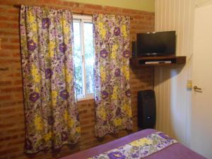 a bedroom with a bed and a window with curtains at Complejo Caramelo in Villa Ventana