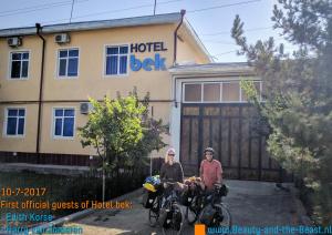 two people on bikes in front of a hotel building at Bek Shahrisabz in Shahrisabz