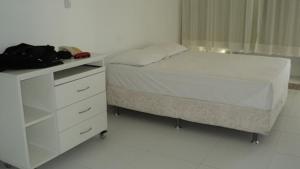 1 dormitorio con cama blanca y vestidor en Studio na praia da Barra, en Salvador