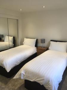 two beds in a room with white sheets at 35 Newvalley in Stornoway