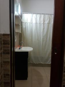ein Bad mit einem Waschbecken und einem Duschvorhang in der Unterkunft Casa centrica Luján in Luján