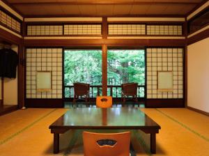 a room with a table and chairs and windows at Syohoen in Daisen