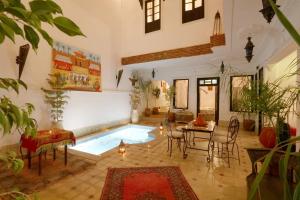 sala de estar con piscina, mesa y sillas en Riad Ibiza Star en Marrakech