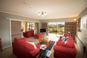 a living room with two red couches and a television at Kowhai Lane Lodge in Half-moon Bay