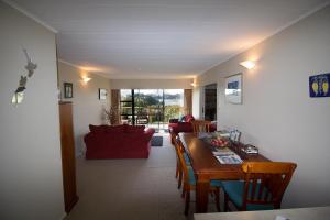 uma sala de estar com uma mesa e um sofá vermelho em Kowhai Lane Lodge em Half-moon Bay