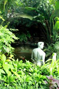 a statue sitting next to a pond in a garden at Club One Seven Gaymen Chiang Mai in Chiang Mai