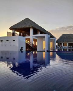 a villa with a swimming pool in the sunset at Hotel Maya Jade in Monterrico