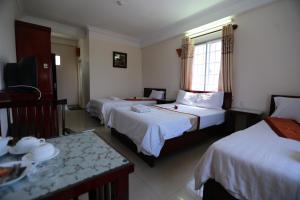 a hotel room with three beds and a table at Nhiet Doi Hotel in Tuy Hoa +30 photos